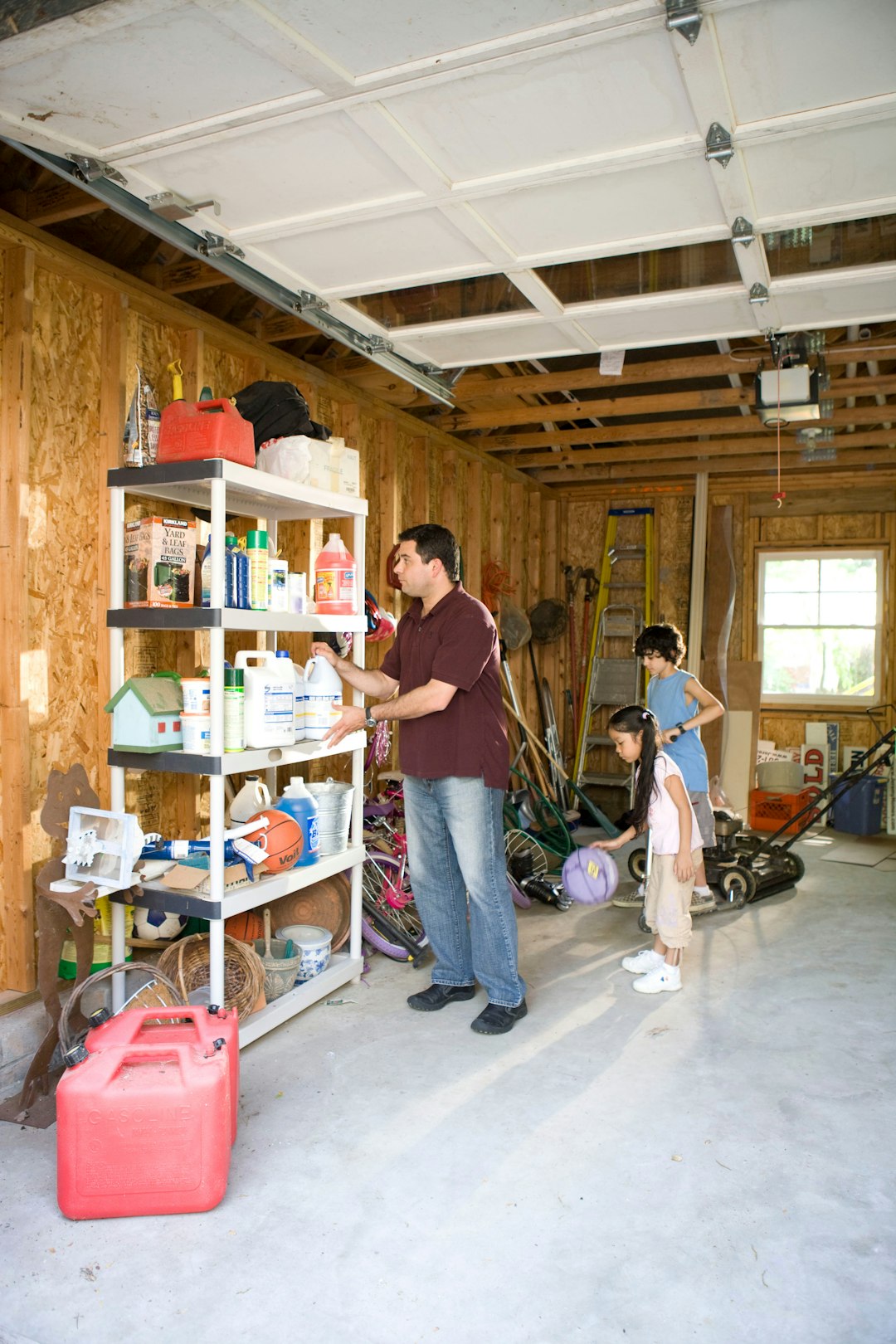 Home Here we see a father organizing his garage contents, while two of his children entertained themselves with some of the playthings stored inside.
